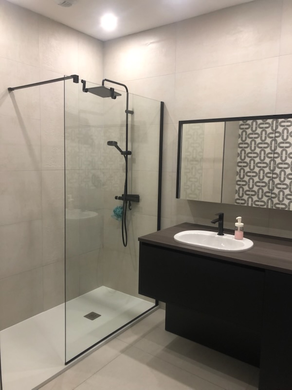 Salle de bain avec douche à l'italienne, carrelage travertin beige et robinetterie noire — Hérault