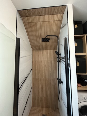 Douche italienne design avec paroi noire, revêtement bois et plafond lamelles — Hérault