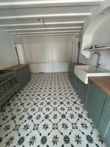 Cuisine avec carrelage cimenté motif étoiles vert et blanc, plan de travail bois