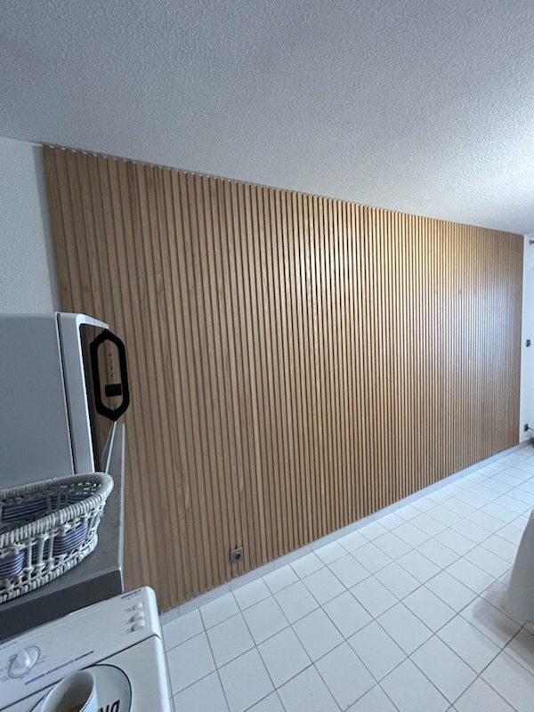 Mur en lambris bois clair dans pièce de vie, sèche-serviettes blanc