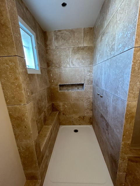 Douche en pierre travertin avec banquette intégrée et niche murale — Hérault